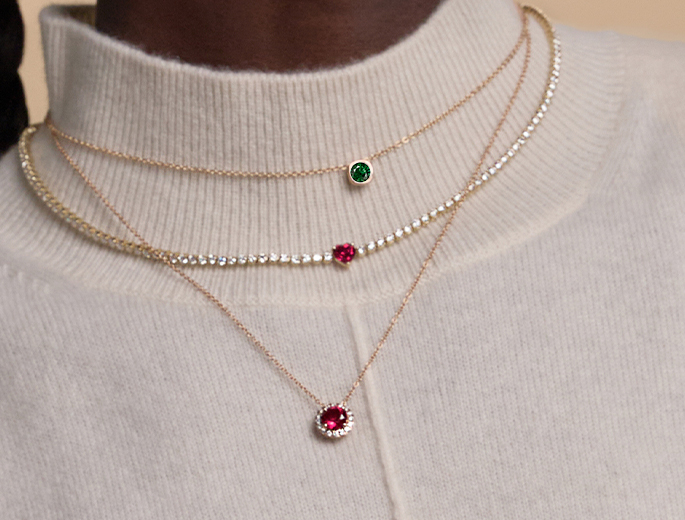 A woman wearing three different types of gemstone necklaces