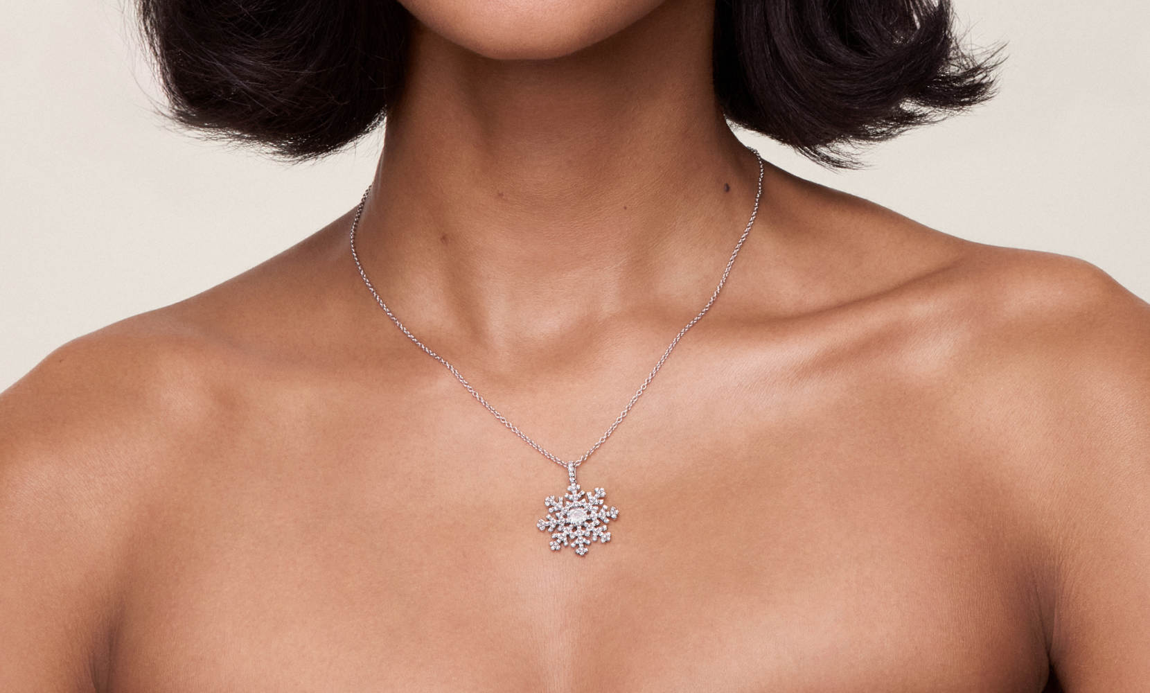 Side profile of a female model wearing three fashion necklaces and diamond hoops